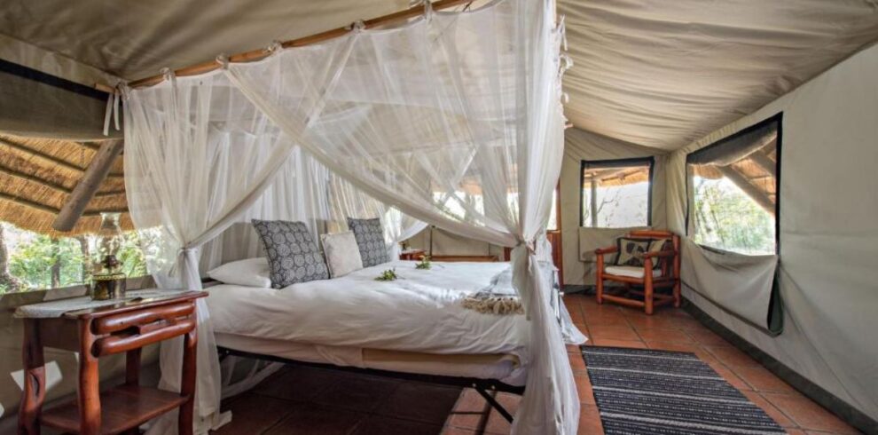 Luxury bed with mosquito netting inside a Meru-style tent at Pungwe Safari Camp